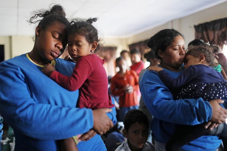 Families worship during a prayer service at a church shelter for migrants who are seeking asylum in El Paso, Texas, on May 18, 2019. © Mario Tama/Getty Two women holding young children in their arms